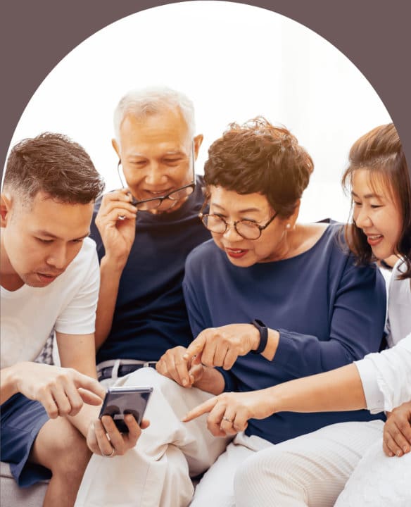This photo shows adult children and their parents looking at a cell phone.